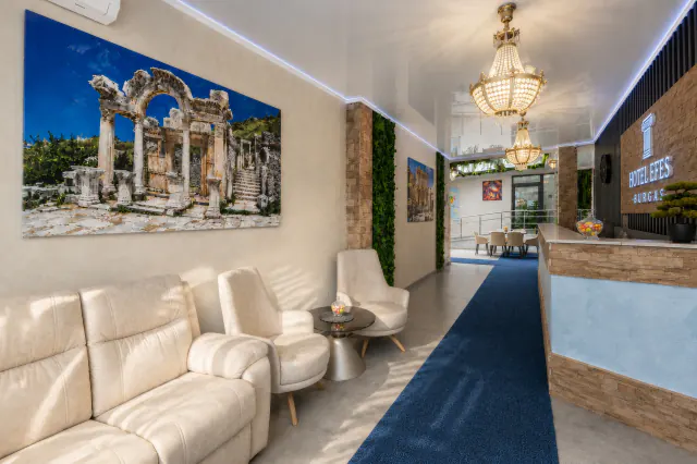 Lobby hotelu Efes s béžovými pohovkami, křesly a obrazem se zříceninami antického Efesu.