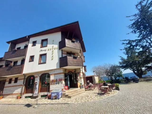 Готель із написом Hotel St. Stefan і кавʼярня перед ним, праворуч — море