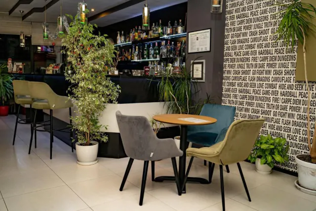 Lobby bar hotelu Gran Via s lahvemi na policích a sametovými židlemi kolem kulatého stolu.
