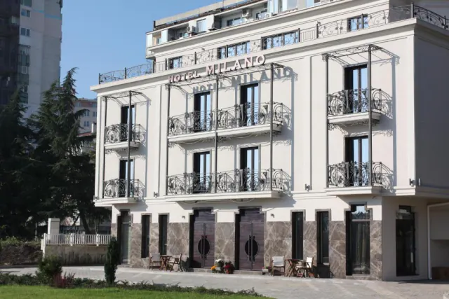 Bílá fasáda rodinného hotelu Milano s kovanými balkony.