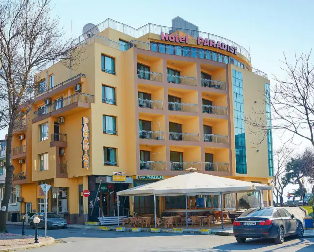 Budova Hotelu Paradise s restaurací pod velkým slunečníkem před vchodem.