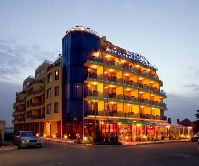 Petar and Pavel Hotel v podvečer – osvětlená fasáda a letní zahrádka restaurace.