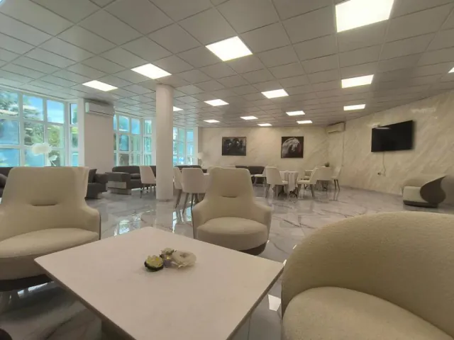 Prostorná společenská místnost s bílými křesly, stolky a mramorovou podlahou v Hotel & Rehabilitation Center St George.