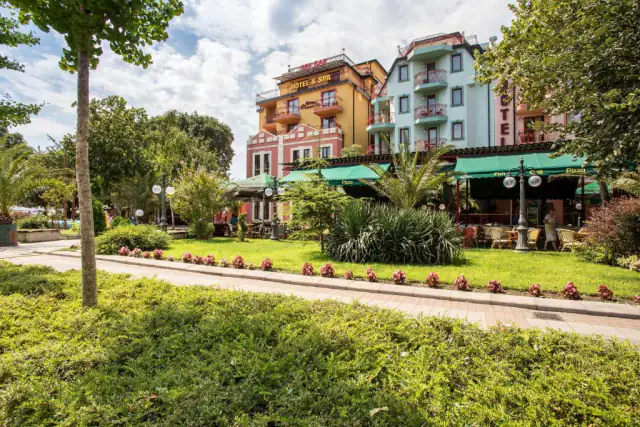 Budovy hotelu Saint George a restaurace se zelenými markýzami za zelenou zahradou.