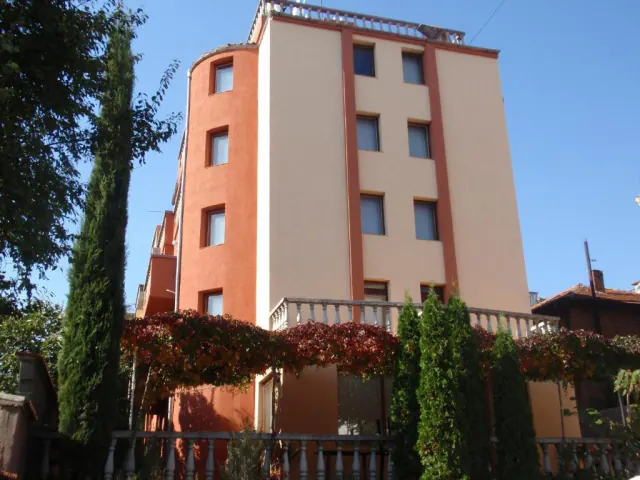 Fasáda rodinného hotelu Sveti Ilija s terasou porostlou divokým vínem a s cypřiši.