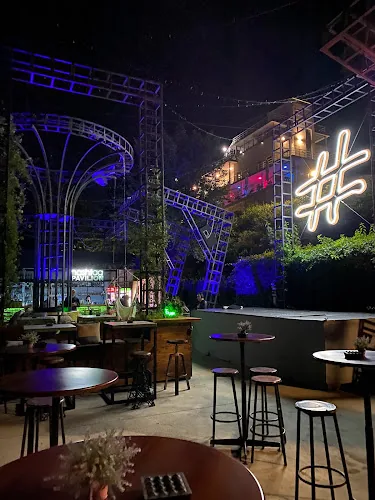 Hashtag Pavilion seara — semn luminos cu neon „#” și structuri iluminate în albastru deasupra tejghelei barului, pe Kraybrezhna Aleya din Burgas.