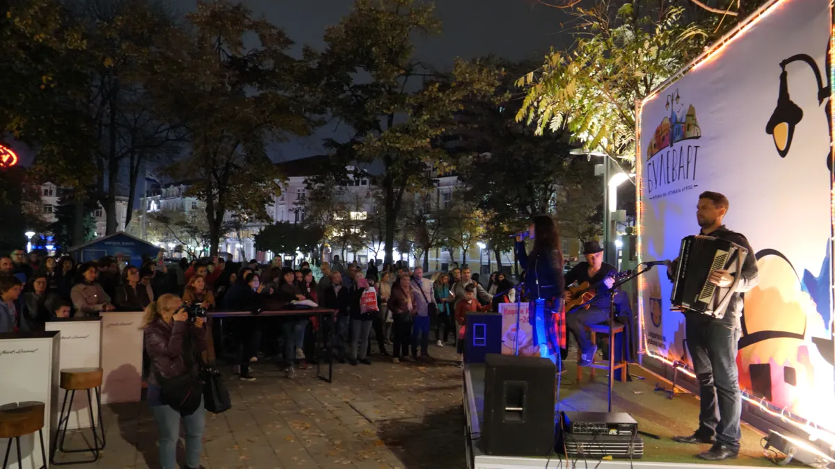 An evening concert at the Boulevart Stage — a singer, a guitarist and an accordionist in front of an audience, with the lit Boulevart backdrop behind them.