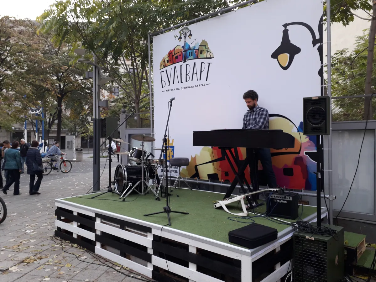 The stage on Vazrazhdane Street — a low platform with green turf, a drum kit and a keyboard player in front of the backdrop with the Boulevart logo and the Burgas coat of arms.
